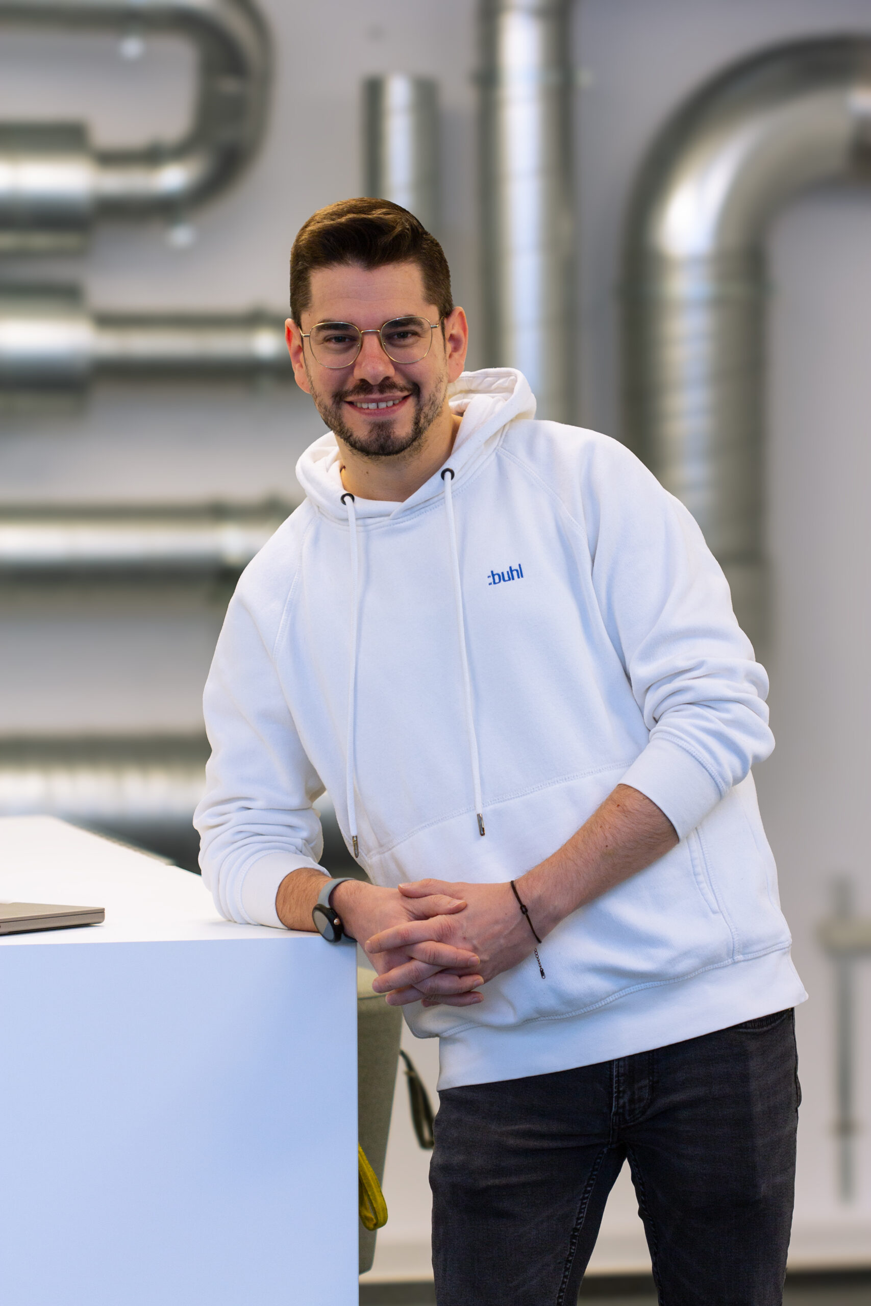 Stefan Knuth, Customer Success Manager bei WISO MeinBüro, lehnt an einem Tisch mit Laptop, im Hintergrund ist ein Konferenzraum zu sehen.